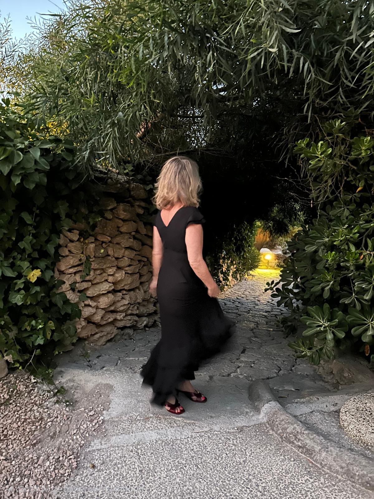 Joanne loopt weg over een stenen pad tussen de bomen, avond op Ibiza